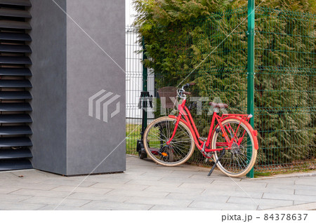 Red bicycle stands outside a city office building strapped on bicycle security cable Red bicycle stands outside a city office building strapped on bicycle security cable 84378637