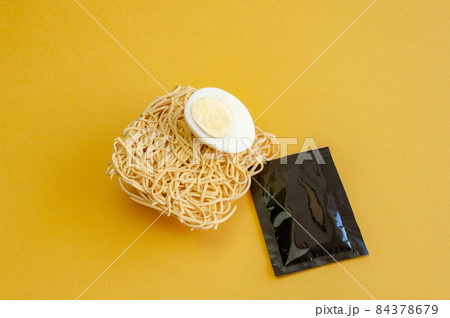 Close-up of boiled egg on instant noodle on yellow background. Blank label sachet 84378679
