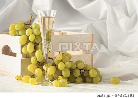 Glass of white wine and grape cluster. Glass of white wine and grape cluster. 84381393