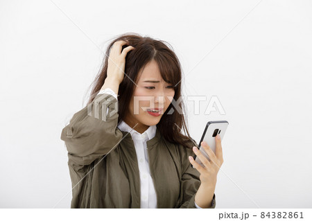 スマホを見て焦る女性 スマホを見て焦る女性 84382861