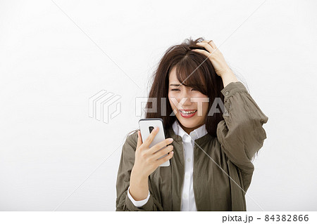 スマホを見て焦る女性 スマホを見て焦る女性 84382866