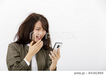 スマホを見て焦る女性 スマホを見て焦る女性 84382869