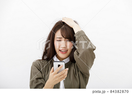 スマホを見て焦る女性 スマホを見て焦る女性 84382870