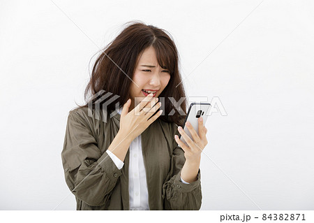 スマホを見て焦る女性 スマホを見て焦る女性 84382871