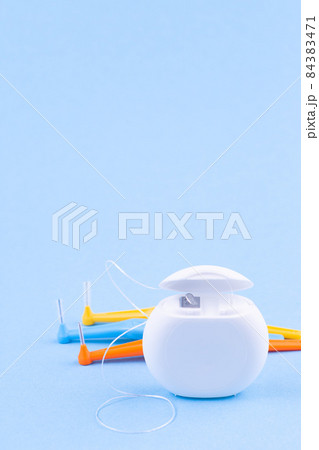 Dental floss and interdental brush angles on blue background, vertical, copy space 84383471