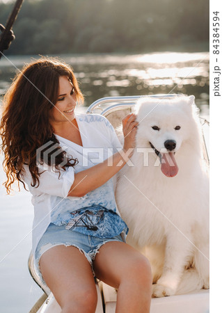 a happy woman with a big white dog on a white yacht in the sea 84384594