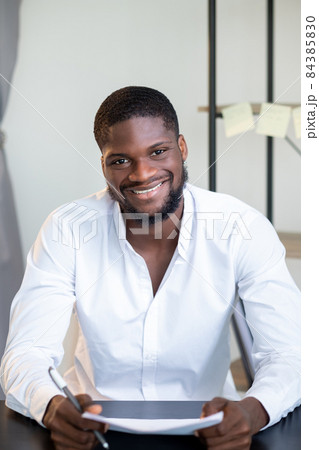 Business coaching. Online interview. Corporate webinar. Portrait of confident successful smiling male entrepreneur at light home office workplace interior. Business coaching. Online interview. Corporate webinar. Portrait of confident successful smiling male entrepreneur at light home office workplace interior. 84385830
