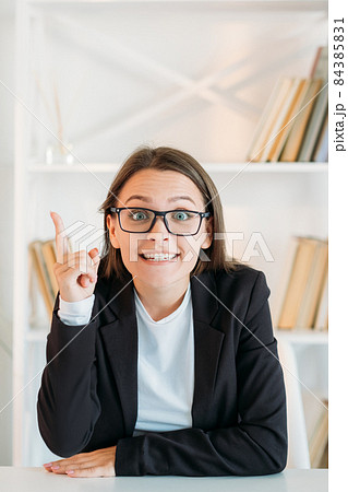 Business idea. Aha insight. Professional strategy. Inspired enthusiastic excited smart woman in eyeglasses pointing up at free space in light office interior. Business idea. Aha insight. Professional strategy. Inspired enthusiastic excited smart woman in eyeglasses pointing up at free space in light office interior. 84385831