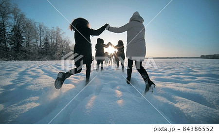 Cheerful girls run across the snow-covered field. Cheerful girls run across the snow-covered field. 84386552