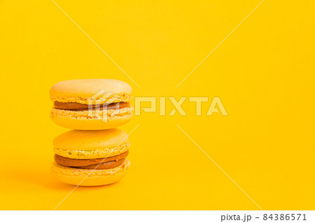 Sweet almond colorful yellow macaron or macaroon dessert cake isolated on trendy yellow modern fashion background. French sweet cookie. Minimal food bakery concept. Copy space 84386571