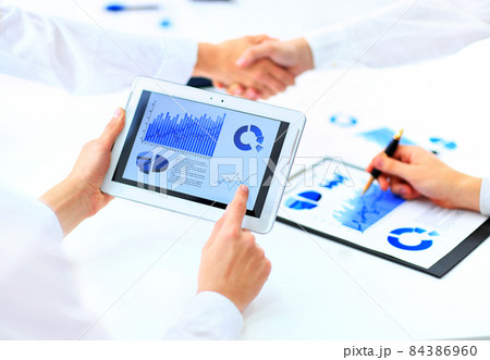 Image of human hand pointing at touchscreen with business document 84386960