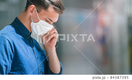 young man in a protective mask talking on a smartphone. 84387395