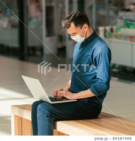close up. a man using his laptop while sitting on a bench close up. a man using his laptop while sitting on a bench 84387408