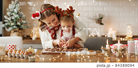 Happy family mother and son in aprons making Christmas cookies together at home Happy family mother and son in aprons making Christmas cookies together at home 84389094