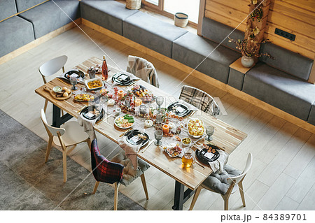 Several chairs around large wooden dining table served with homemade food 84389701