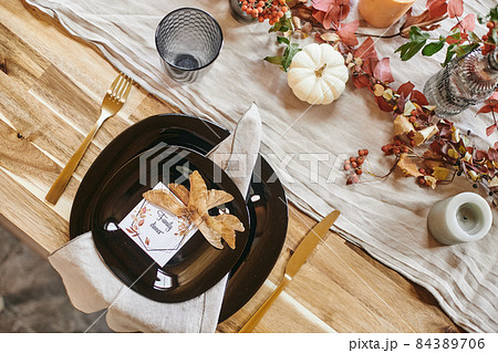 Flatlay of plates with invitation for family dinner and dry autumn leaves Flatlay of plates with invitation for family dinner and dry autumn leaves 84389706