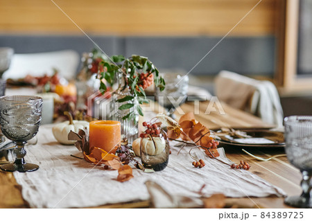 Still life of autumn leaves in vase and bottle on served festive table Still life of autumn leaves in vase and bottle on served festive table 84389725