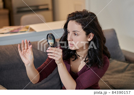 Focused attractive female examining a crystal through a magnifier 84390157