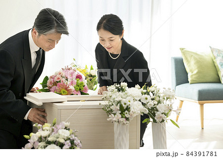 棺の中を見つめるミドルの男女　家族葬　自宅葬イメージ 84391781