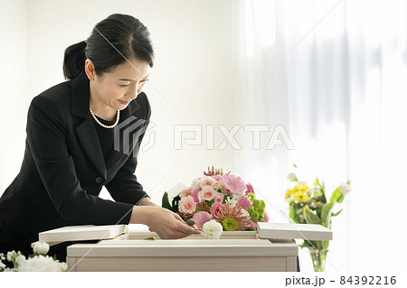 棺に花を入れる喪服姿の女性 84392216