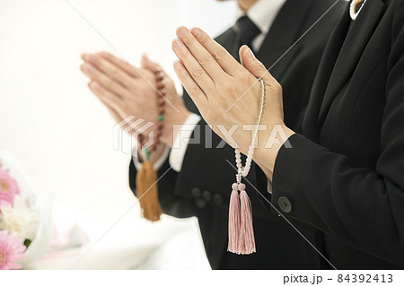 葬儀　イメージ　数珠を持ち手を合わせる男女の手元 84392413
