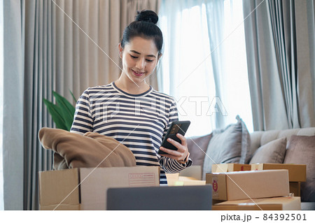 Asian small business owner checking order by smartphone at home office. Business retail market and online sell marketing delivery, SME e-commerce concept. Asian small business owner checking order by smartphone at home office. Business retail market and online sell marketing delivery, SME e-commerce concept. 84392501