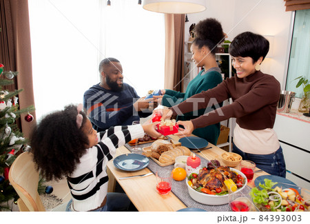 Happy family with daughter giving gift box with father and mother during dinner at home. Happy family with daughter giving gift box with father and mother during dinner at home. 84393003