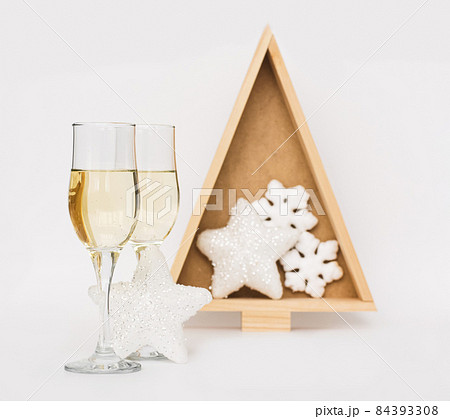 Champagne in two elegant glasses, Christmas tree, toys light background. Festive winter holidays Christmas and New Year 84393308