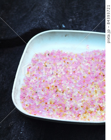 used pink coloured blue silica gel from a camera lens keeping box in plastic dish on house roof in sun drying process for reuse 84393721