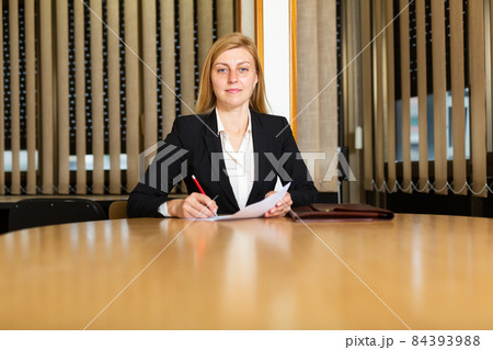 Portrait of smiling businesswoman in modern office at negotiating table Portrait of smiling businesswoman in modern office at negotiating table 84393988