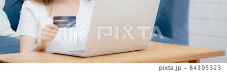 Young asian woman sit on sofa using laptop computer shopping online with credit card. 84395323