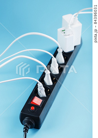 A black mains filter with electrical outlets inserted into it with white plugs of electrical appliances on a blue background A black mains filter with electrical outlets inserted into it with white plugs of electrical appliances on a blue background 84396031