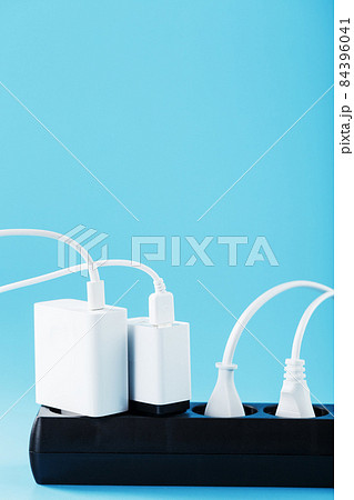 A black mains filter with electrical outlets inserted into it with white plugs of electrical appliances on a blue background A black mains filter with electrical outlets inserted into it with white plugs of electrical appliances on a blue background 84396041