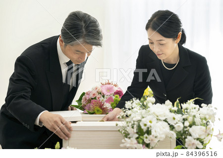 棺の中を見つめるミドルの男女　家族葬　自宅葬イメージ 84396516