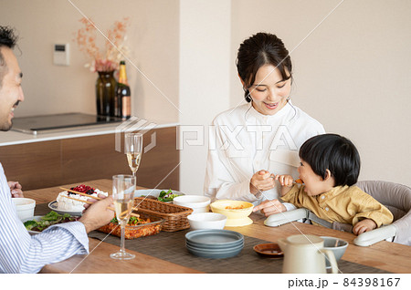 ご飯を食べさせる美人なママさんと見守るパパの幸福な食卓 ご飯を食べさせる美人なママさんと見守るパパの幸福な食卓 84398167