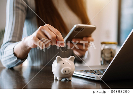 woman hand putting coin into piggy bank .. woman hand putting coin into piggy bank .. 84398290