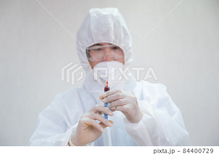 Doctor in medical ppe holding syringe injecting blood sample in the laboratory Doctor in medical ppe holding syringe injecting blood sample in the laboratory 84400729