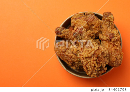 Bucket with fried chicken on orange background Bucket with fried chicken on orange background 84401793