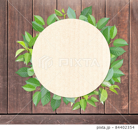 Green leaves and round paper card on wood texture. Horizontal banner with eco paper texture Green leaves and round paper card on wood texture. Horizontal banner with eco paper texture 84402354