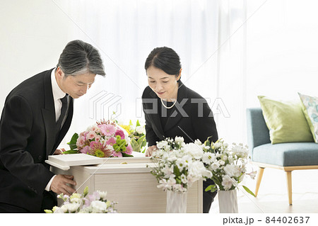 棺の中を見つめるミドルの男女　家族葬　自宅葬イメージ 84402637