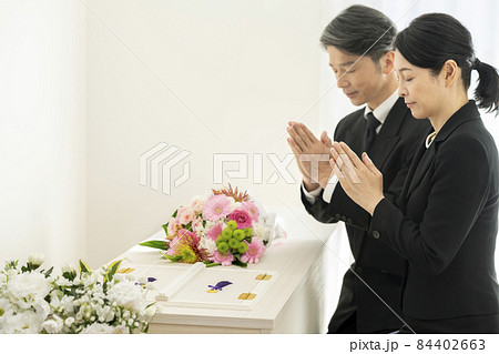 棺の前で手を合わせる喪服姿の男女 棺の前で手を合わせる喪服姿の男女 84402663