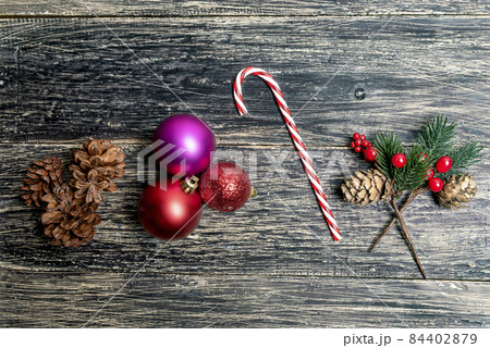 Pine Cone with a candy cane and colorful Christmas ball on wooden background Pine Cone with a candy cane and colorful Christmas ball on wooden background 84402879