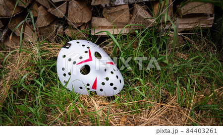 Creepy white hockey mask lays on the ground near with woods 84403261