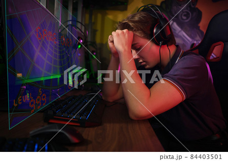 Professional young caucasian gamer playing online on his PC. He upset because of losing the game 84403501