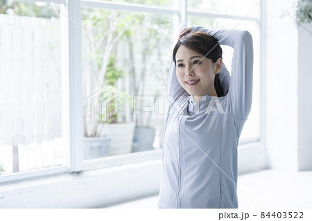 窓辺でストレッチをする若い女性 84403522
