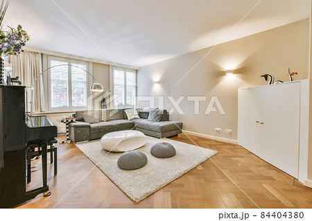 Comfortable sofa and armchair placed on soft carpet near windows in cozy light living room in modern flat Comfortable sofa and armchair placed on soft carpet near windows in cozy light living room in modern flat 84404380
