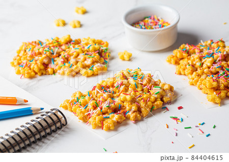 Children corn stars cereal bars with colored sprinkles and white chocolate on a white background. Children corn stars cereal bars with colored sprinkles and white chocolate on a white background. 84404615