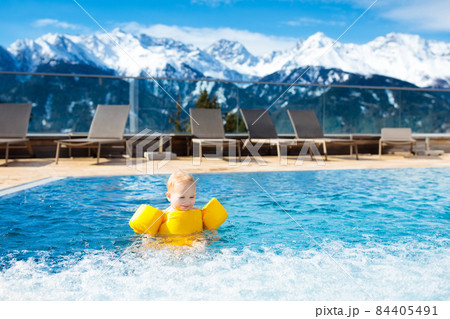 Child in outdoor swimming pool of alpine resort 84405491