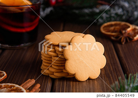 Gingerbread cookies in a stack with spices on a wooden background and spruce branches in the back.  84405549