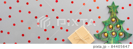 Banner with a Christmas tree, present and red confetti on a gray background. Christmas card. Flat lay, copy space. Banner with a Christmas tree, present and red confetti on a gray background. Christmas card. Flat lay, copy space. 84405647